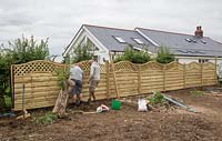 Men levelling fencing panels to ensure straight line