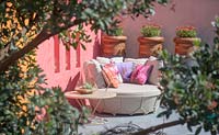 Beneath a Mexican Sky Garden - Sofa with brightly painted walls and pots of osteospermum - RHS Chelsea Flower Show