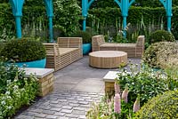 Wooden table and benches with blue metal arches and granite cobbles and clipped yew balls  in planters  - The Sir Simon Milton Foundation Garden: '500 years of Covent Garden' - RHS Chelsea Flower Show 2017 - Designer: Lee Bestall - Sponsor: Capco Covent Garden