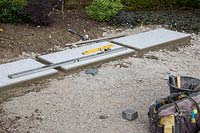 Making a mixed material patio - First row of large porcelain paving slabs laid on foundation of compressed finely crushed concrete