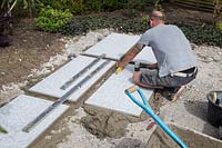 Making a mixed material patio - man using spirit level to ensure that large porcelain slabs are level