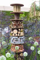 Insect house surrounded by white Allium balls in Greening Grey Britain Garden - RHS Chelsea Flower Show 2017 