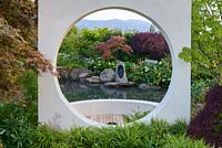 Japanese style garden framed with 'Moongate' window, with sunken circular area with planting of Acer palmatum, Zantedeschia aethiopica, Hakonechloa macra, and Gunnera manicata by  large pool - 'At One With...A Meditation Garden' - Howle Hill Nursery, RHS Malvern Spring Festival 2017