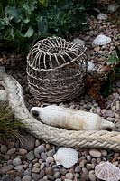 Woven lobster pot, fishing float and maritime rope with Crambe maritima - Sea Kale,  pebbles and shells.