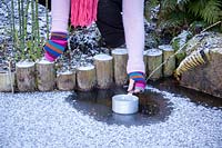 Melting ice on a frozen pond with a saucepan of hot water