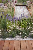 Agastache foeniculum and Gaura lindheimeri with Achillea millefolium 'Sally' and Pennisetum 'Red Buttons' growing around a fibreglass water trough with rusty effect finish full of pebbles in the 'Business and Pleasure' Garden at Tatton RHS Flower Show 2017