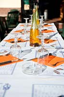 restaurant table set for lunch, wine glasses, orange napkins and olive oil, France