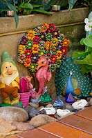 Clorful garden ornaments including garden gnome and flowers made from beads, June.