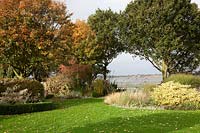 View of the River Stour Estuary through island beds planted with shrubs and grasses including, Miscanthus, Stachys, Phormium, Euonymus and Stipa tenuissima.