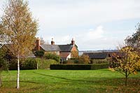 View of the house with Autumnal trees including Betula pendula and a view of the River Stour Estuary.