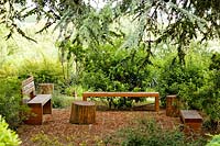 Wooden seating under trees on patio in Potenza Picena. Project garden, Macerata, Italy, June.