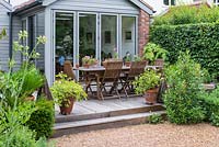 Overlooking a gravel area, a kitchen extension and raised wooden terrace