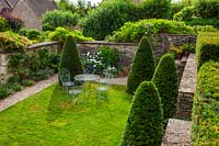 Yew cones on lawn with table and chairs, Burford, Oxfordshire.