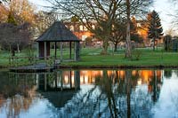 House and summerhouse reflected in lake, Chippenham Park, Cambridgeshire.
