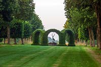 Lawn and avenue of Tilia platyphyllos 'Rubra' with central yew Rondel enclosing bronze stag sculpture