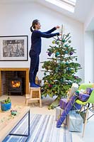 Woman decorating Peacock colour themed Christmas tree.