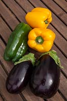 Colourful vegetables - Peppers and Aubergines - outdoors on a wooden table