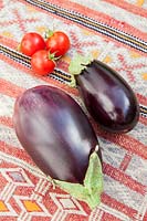Fresh Aubergines and cherry tomatoes on a kilim covered table