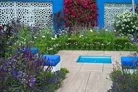 A blue and white themed Mediterranean style garden with cube seats, Bougainvillea and a small pool