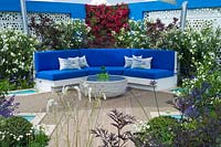 Bougainvillea on a blue wall and a paved seating area with pool in a blue and white Mediterranean style garden