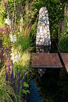 Contemporary garden with stone sculpture feature set in a rectangular pool of water