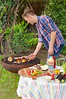 Young man is barbequeing in the garden