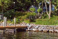 Wooden jetty leading from lake edge and American terraced garden