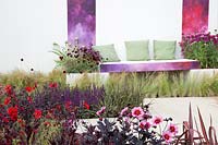 Contemporary patio with Dahlia, Dianthus, Anemone and ornamental grasses, sitting area in the background