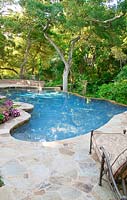 Swimming pool framed with natural stone, lounging chair in the front