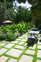 Terrace with natural stone slabs, garden furniture, Canna and perennialborder