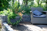 Terrace with plant container, perennial border and garden furniture