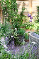Impression with container planting, garden furniture, rose ball and perennials