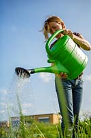 Young woman working in the garden. watering the garden