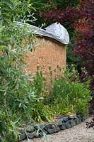 Caervallack, Cornwall, UK. ( McClary/Robinson ) Artists garden in summer, Nectaroscordum siculum against cob wall