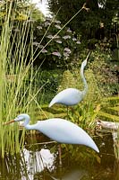 Bourton House Garden, Gloucestershire. Mid summer. Detail of the pond with statue of 'Two Herons' by Michael Lythgoe