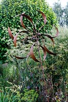 Little Ash Garden, Fenny Bridge, Devon. Autumn garden. Rusted metal 'Windmill' sculpture in autumn border
