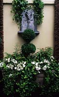 Wall mounted ram s head water feature Design Steve Woodham Boxwood topiary Busy Lizzies and ivy in trough