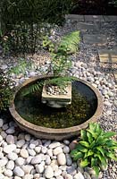 shallow bowl water feature Japanes style in small town garden surrounded with attractive white stone and pebble mulch