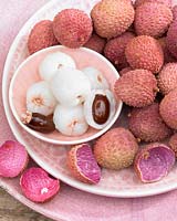 A pile of Litchi chinensis, Lychee, in a pink patterned bowl and plate set. 