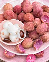 A pile of Litchi chinensis, Lychee, in a pink patterned bowl and plate set.