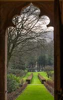 A formal garden and lake as seen from ornate doorway. 