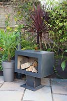 An outdoor fireplace with surrounded by tropical foliage planting. 