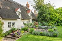 A view of a gravel garden, garden furniture and lawn of thatched cottage. 