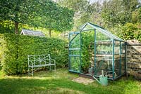 View of small aluminium greenhouse with in town garden. 
