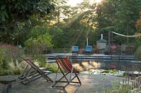 View of seating area at the side of the natural swimming pool at Ellicar Gardens, Nottinghamshire. 
