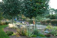 View of seating area at the side of the natural swimming pool at Ellicar Gardens, Nottinghamshire.