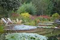 Two deckchairs set on patio by natural swimming pool at Ellicar Gardens, Nottinghamshire.