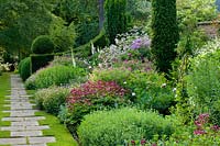 View of flowering beds and borders with formal topiary. 