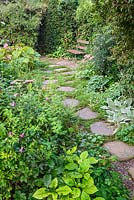 A stone path leading to a garden bench in NGS garden in St Albans, Hertfordshire, UK.

