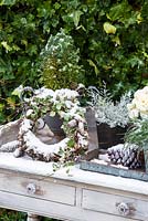 Close up of winter garden decoration on table with wreath, cones and evergreens. 